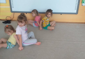 Zajęcia w grupie 5. Dzieci w parach, opierają się do siebie plecami, siedzą na podłodze, przeciągając się w przeciwne strony.